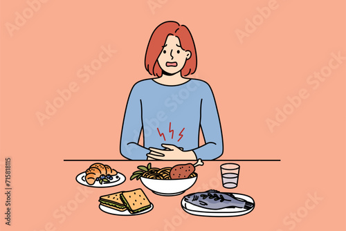 Girl suffers from stomach pain due to digestive problems, sits at dinner table with food. Sick woman needs consultation with nutritionist to restore health of stomach and digestive organs.