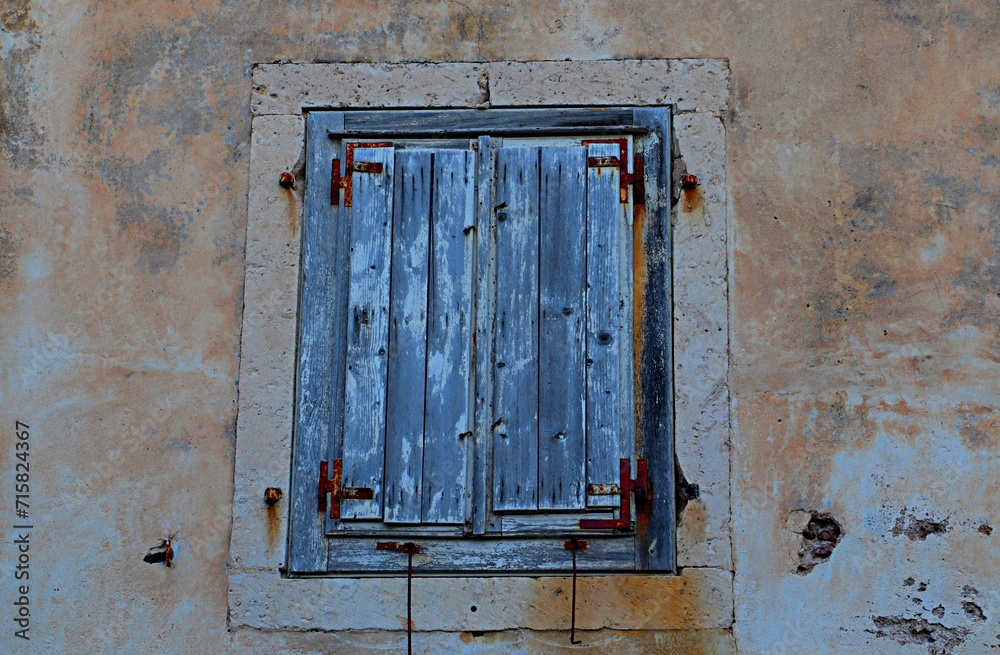 Closed window closed by old gray, weathered wooden shutters