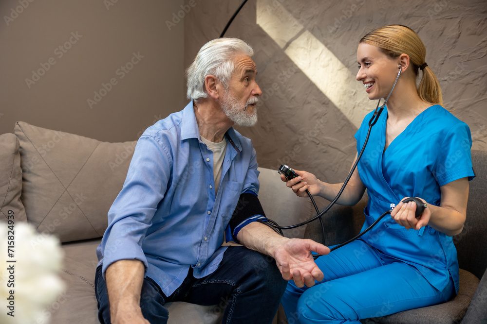 Obraz premium Nurse examining mature patient measuring blood pressure.