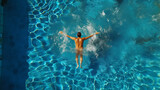 Young man swimming in a pool, aerial view from above