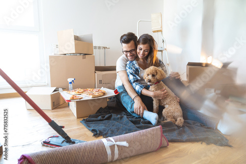 Young beautiful couple moving to a new apartment with their dog together. photo