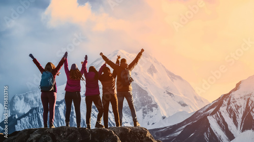 from behind view group of people standing with arms up in front of magical sunset in mountains in success and achievement concepts photo