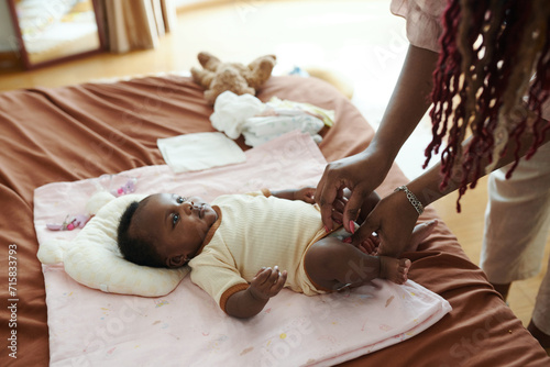 Mother changing diaper of newborn baby girl