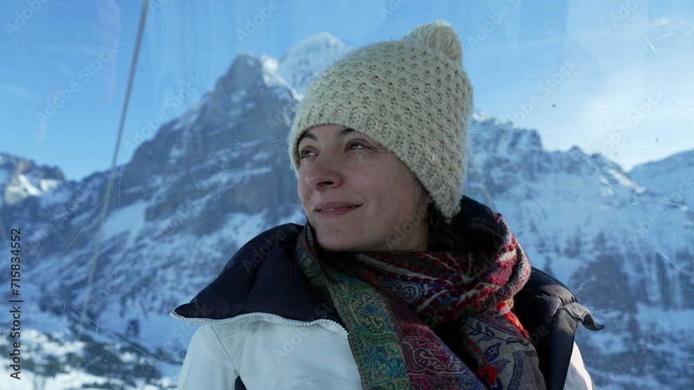 Woman wearing winter clothes enjoying Swiss alps view from high above in mountain peak staring at scenic view Woman wearing winter clothes enjoying Swiss alps view from high above in mountain peak staring at scenic view