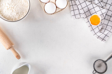 Empty space baking background with bakery ingredients - flour, milk, eggs, rolling pin. Simple pastry baking flat lay top view border