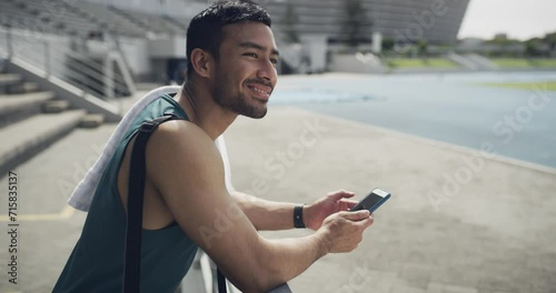 Happy man, fitness and phone typing on break for communication or social media at stadium. Active male person or runner smile in relax or rest on mobile smartphone for online chatting, texting or app photo