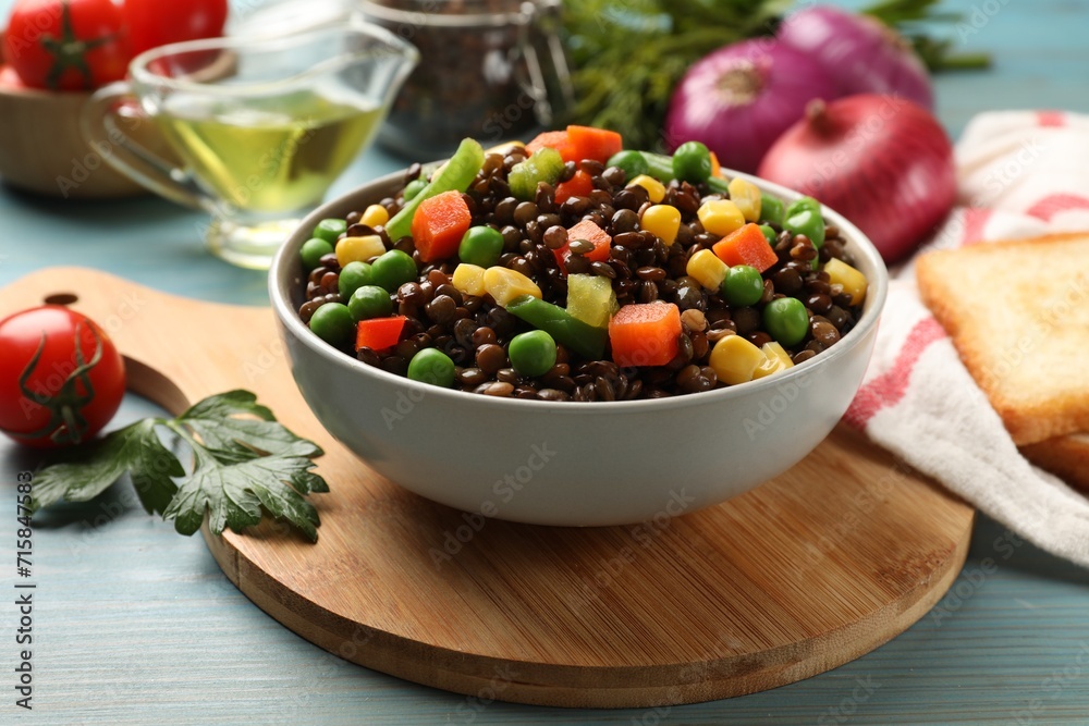 Delicious lentils with vegetables on light blue wooden table, closeup Delicious lentils with vegetables on light blue wooden table, closeup