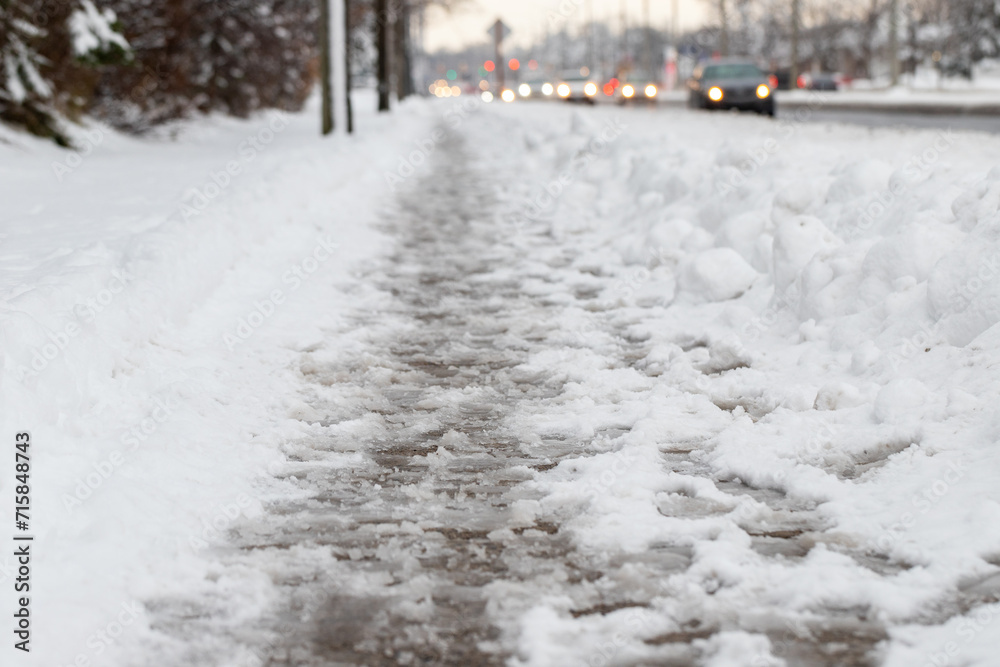 Winter road with melting from salt snow. Close up of sidewalk with slush on snowy day