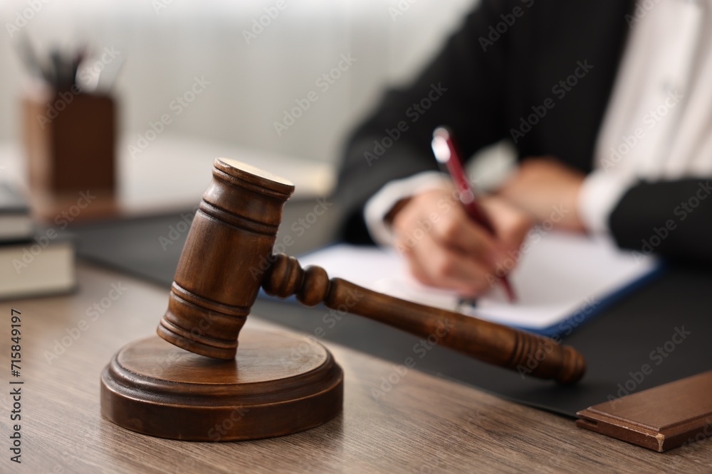 Notary with clipboard writing notes at workplace in office, focus on mallet Notary with clipboard writing notes at workplace in office, focus on mallet