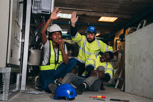 Team Engineers calls for assistance after a team member sustains a leg injury while doing electrical work. Technician in inverter solar panel room.