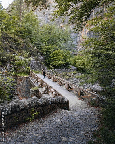 Backpacking woman crosses a bridge in the Pyrenees forest