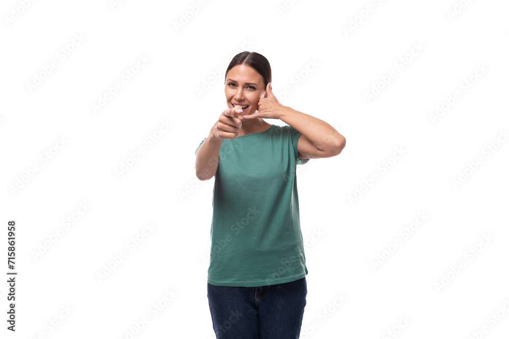30 year old brunette woman with ponytail dressed in a green basic t-shirt smiling on a white background with copy space
