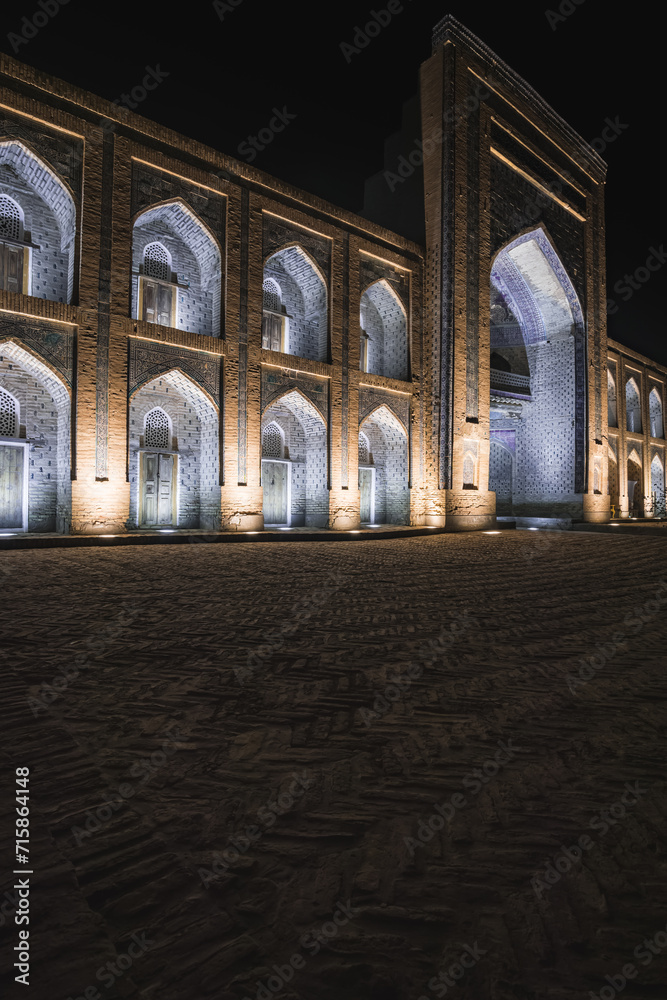 Mohammed Rakhim Khan Madrassah illuminated by lanterns and spotlights in the evening in the ancient city of Fort Khiva in Khorezm, night exterior of the facade of the mausoleum