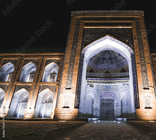 Mohammed Rakhim Khan Madrassah illuminated by lanterns and spotlights in the evening in the ancient city of Fort Khiva in Khorezm, night exterior of the facade of the mausoleum photo