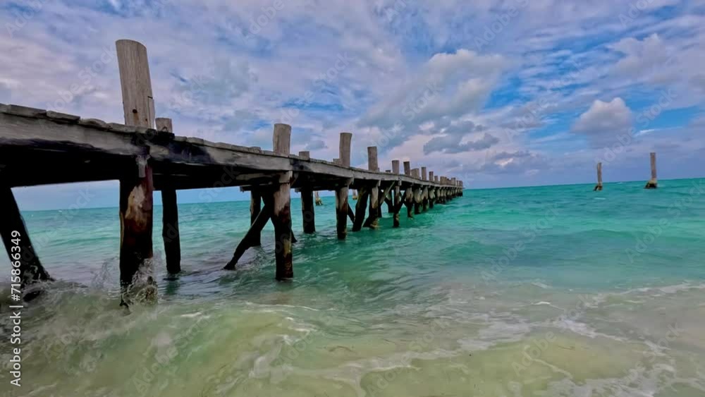 Muelle de madera antiguo sobre el mar caribe y cielo semi nublado