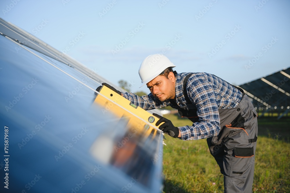 An Indian worker in uniform and with tools works on a solar panel farm An Indian worker in uniform and with tools works on a solar panel farm