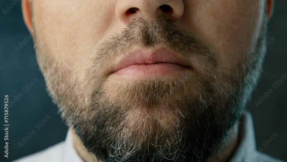 Closeup mad man with angry facial expression is playing with nodules. Cropped mouth of angry bearded 40s man grinding jaw. Frustrated businessman feeling irritation and anger, studio background 4K