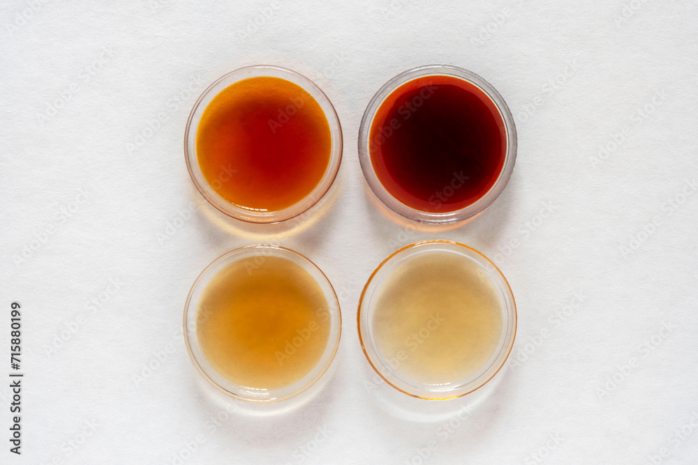 Different classes of maple syrups in different colours in glass dishes ...