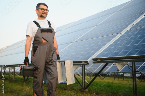 Portrait of senior worker in uniform standing near solar panels
