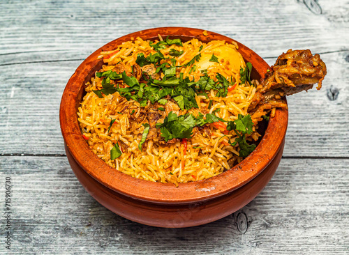 chicken hyderabadi biryani served in claypot isolated on wooden table top view of indian spicy food photo