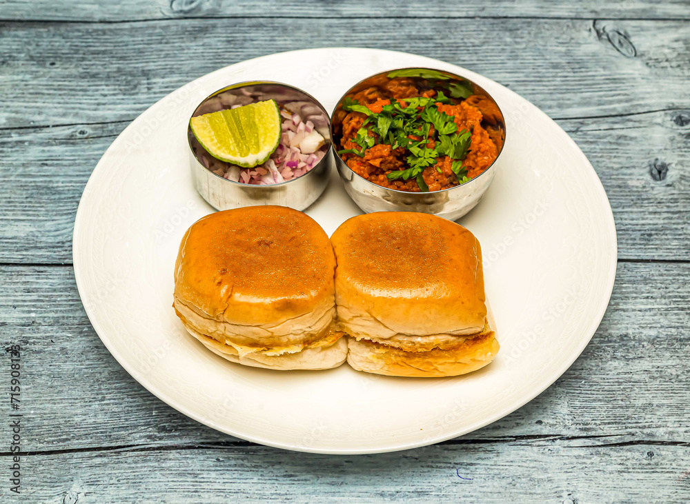 chicken pav bhaji or vada pav bun kabab with lemon and onion served in dish isolated on wooden table top view of indian spicy food chicken pav bhaji or vada pav bun kabab with lemon and onion served in dish isolated on wooden table top view of indian spicy food