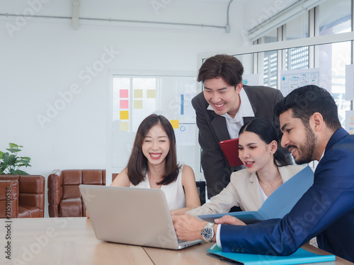 Portrait business team woman and man Asian group meeting sitting on desk looking computer hand holding laptop notebook ready for idea new project happy working online sale inside the home office © Singh