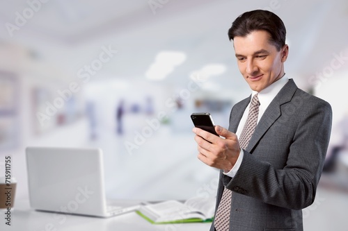 Smiling business man using mobile phone in office
