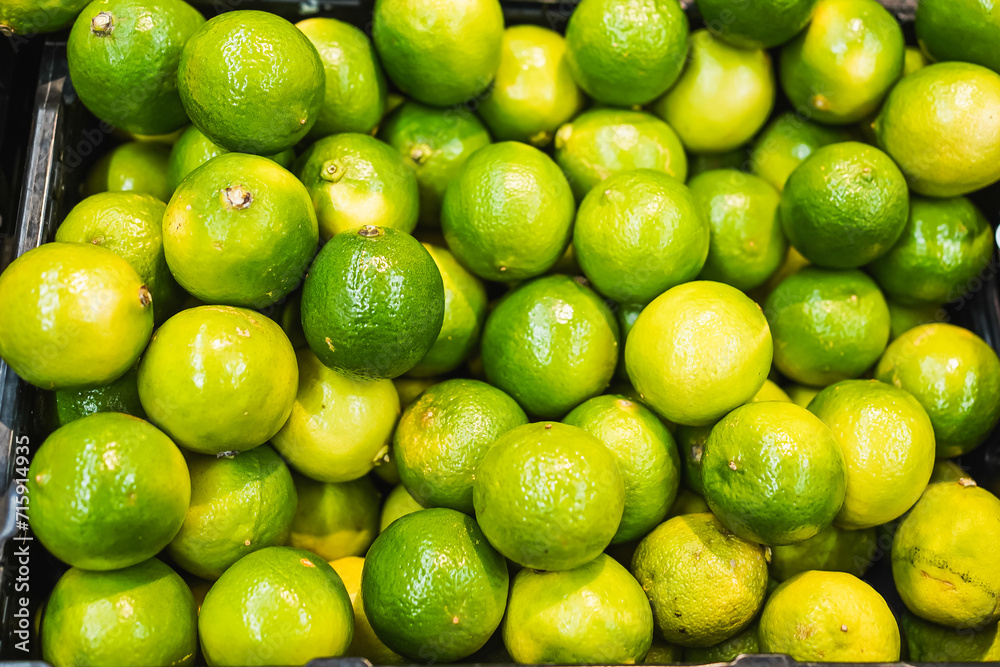 Fresh green limes stacked in a produce bin at a grocery store. Fresh green limes stacked in a produce bin at a grocery store.
