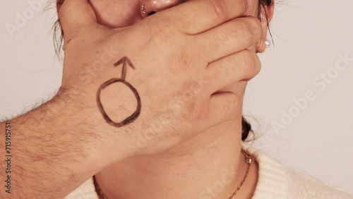 Man covering the mouth of a woman with the man symbol painted on his hand.