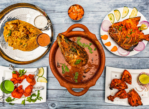 fish head curry, darbar royal potlam biryani rice, tandoori chicken, grill pomfret fish, Rava kesari halwa sweet, chicken lollipop, served in dish isolated wooden table top view of indian spicy food photo