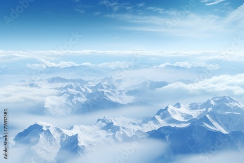  a view of the top of a mountain range from a plane in the air with a blue sky and white clouds.