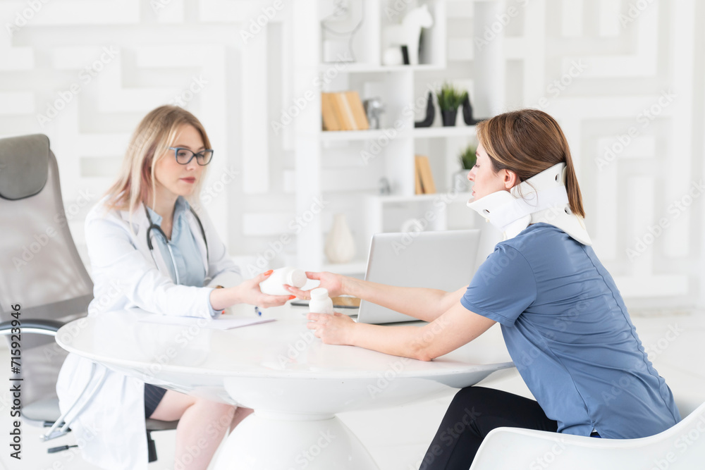 Obraz premium Female doctor traumatologist-orthopedist explaining to her patient with serious neck injury in neck brace about importance of cervical collar for healthy cure