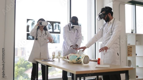 Education, science, vr, medical and health concept. Group of multiethnic doctors, biologists, archeologists, scientists wearing VR goggles study human skeleton in modern laboratory. photo