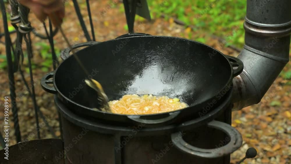 Cooking outdoors with cast iron pan. Frying onion. 4k video footage UHD 3840x2160 Cooking outdoors with cast iron pan. Frying onion. 4k video footage UHD 3840x2160
