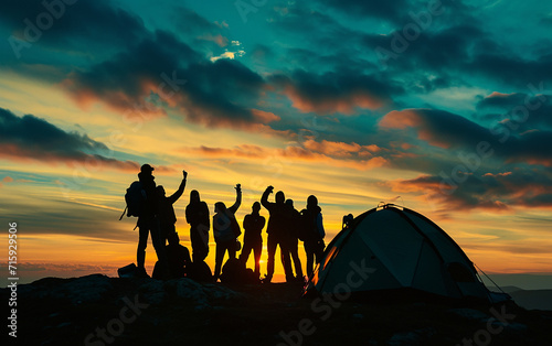 Uma silhueta de um grupo de pessoas se diverte no topo da montanha perto da tenda durante o pôr do sol photo