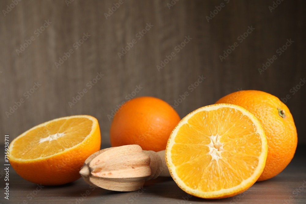 Fototapeta premium Fresh ripe oranges and reamer on wooden table