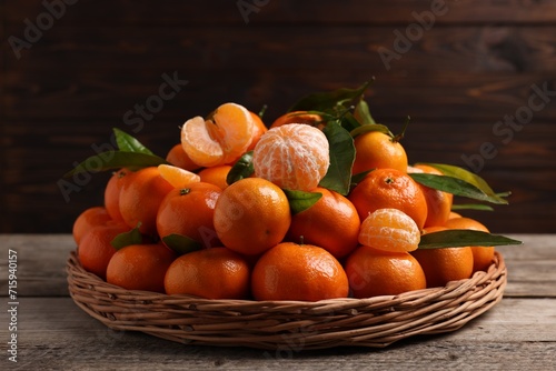 Fresh ripe juicy tangerines and green leaves on wooden table