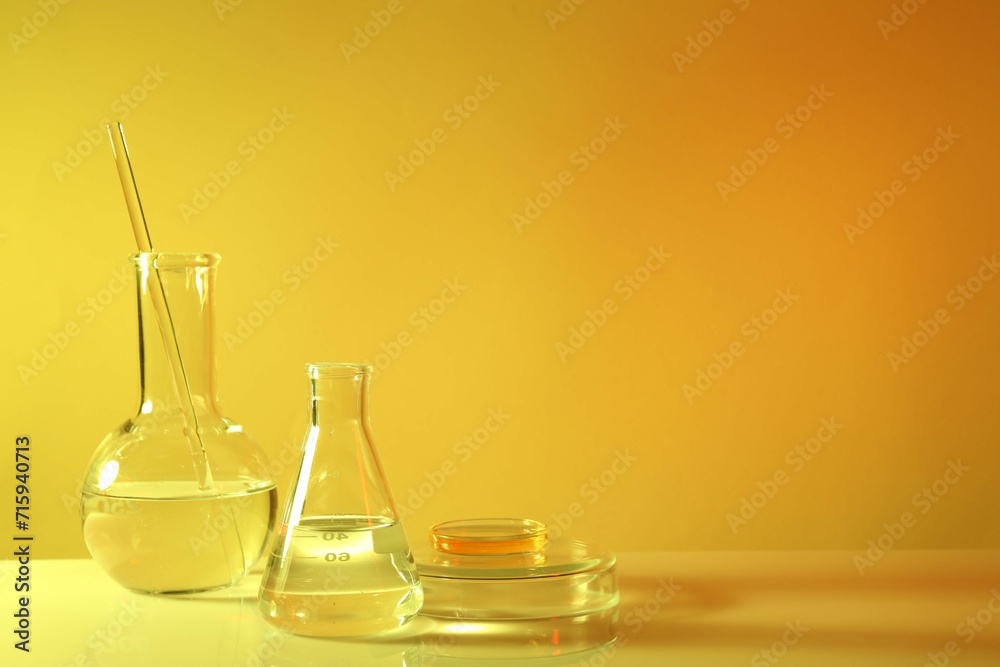 Laboratory analysis. Different glassware on table against yellow background, space for text