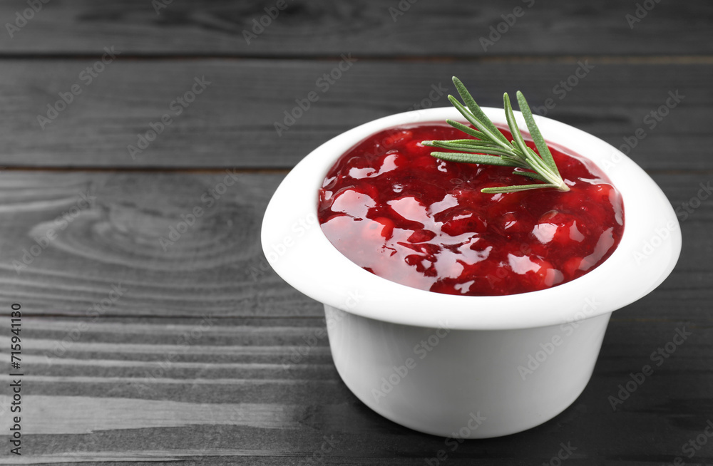Fresh cranberry sauce in bowl and rosemary on black wooden table, closeup. Space for text Fresh cranberry sauce in bowl and rosemary on black wooden table, closeup. Space for text