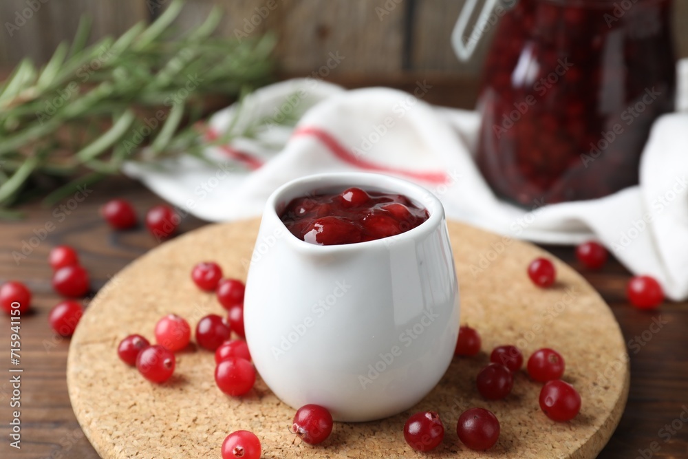 Cranberry sauce in pitcher and fresh berries on wooden table Cranberry sauce in pitcher and fresh berries on wooden table
