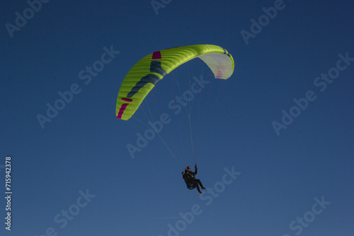 yellow paraglider. Person who paraglides. Paragliding in a blue sky photo