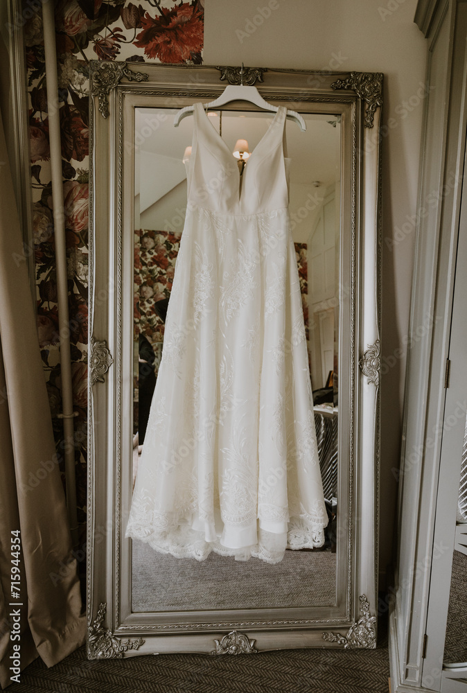 white wedding dress hanging on a mirror