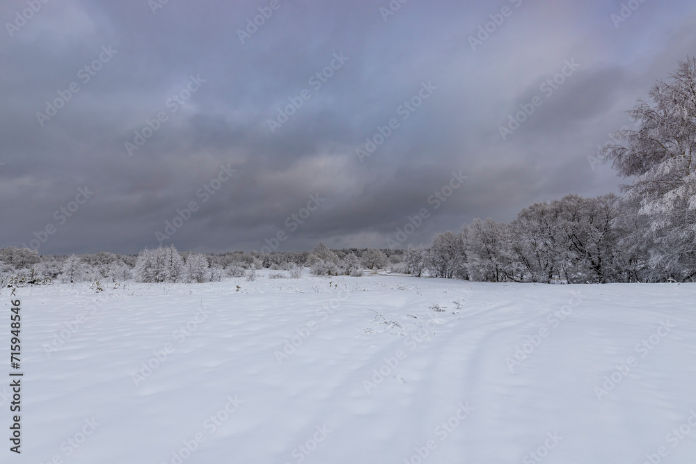 Dramatic blue sky with clouds over snowy field