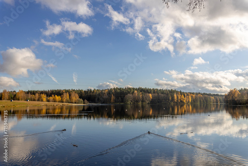 Clouds are reflected in the river, Autumn landscape with a river and trees along the shore.