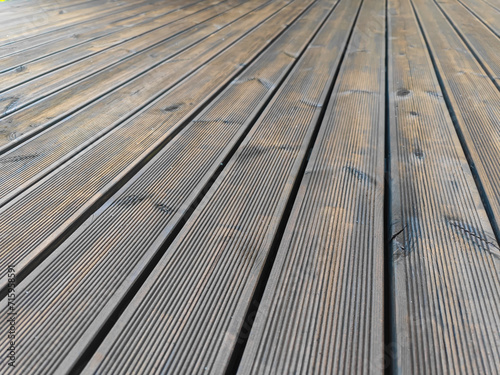 Fluted pine wood terrace freshly impregnated with dark brown oil. Decking of renovated old wooden planks