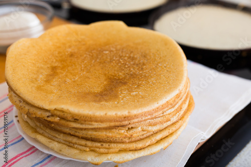 Process of baking pancakes in pans on kitchen stove. stack of hot pancakes