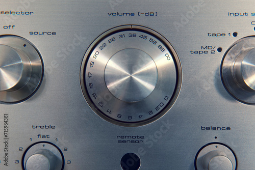 Macro of a vintage amplifier, and its volume dial in decibels. Other knobs for controlling it can be seen around it.