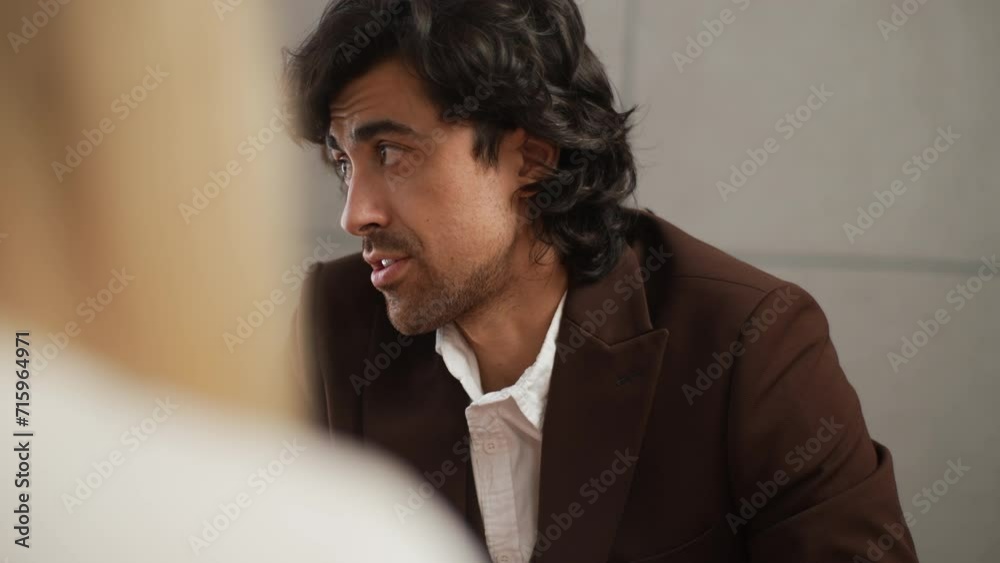 Portrait of confident businessman in suit talking to business colleagues or partners sitting at conference table. Male leader discussing work at team meeting or group negotiations having conversation. Portrait of confident businessman in suit talking to business colleagues or partners sitting at conference table. Male leader discussing work at team meeting or group negotiations having conversation.
