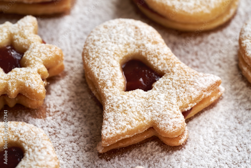 Linzer Christmas cookie filled with strawberry marmalade and dusted with sugar on a wooden table