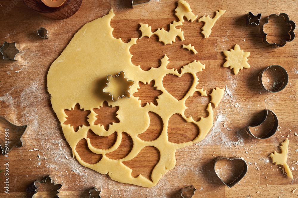 Cutting out shapes from rolled out dough to prepare Linzer Christmas cookies, top view Cutting out shapes from rolled out dough to prepare Linzer Christmas cookies, top view